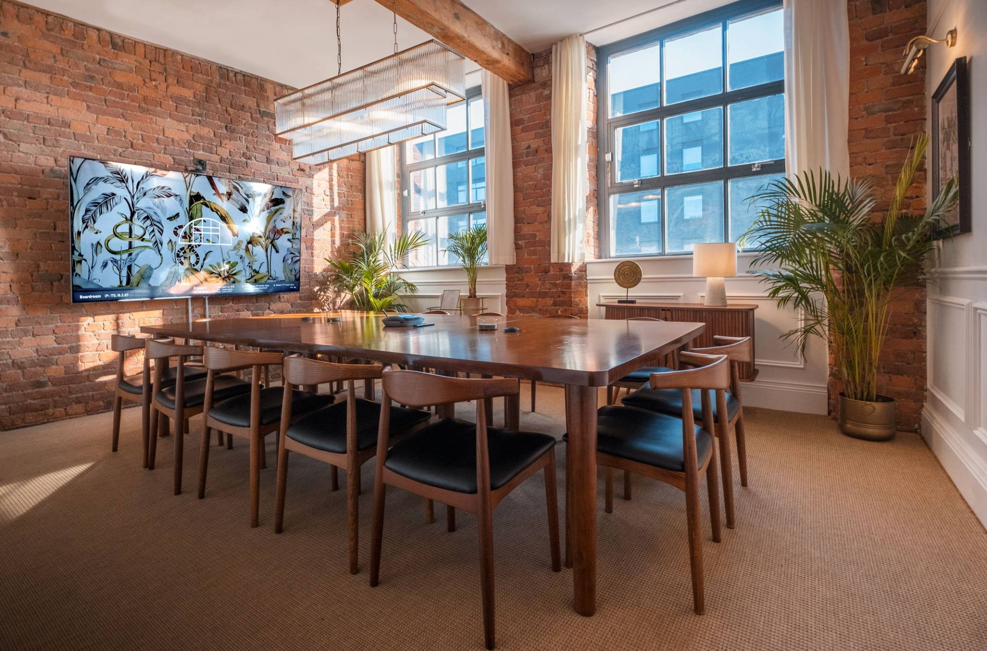 Beehive Lofts Boardroom in Manchester featuring an 85-inch HDR 4K screen, teleconference technology, and white boards, seating 14 people